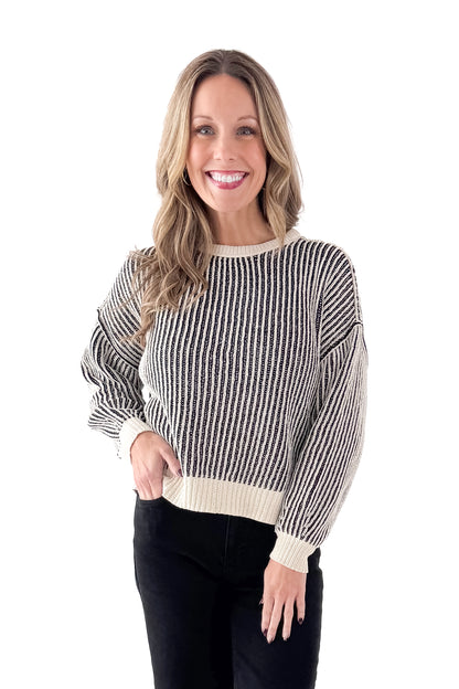 Front view of woman wearing Black &amp; Cream Striped Sweater with jeans against white studio background.