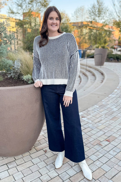 Front view of woman wearing Black &amp; Cream Striped Sweater with jeans outside.