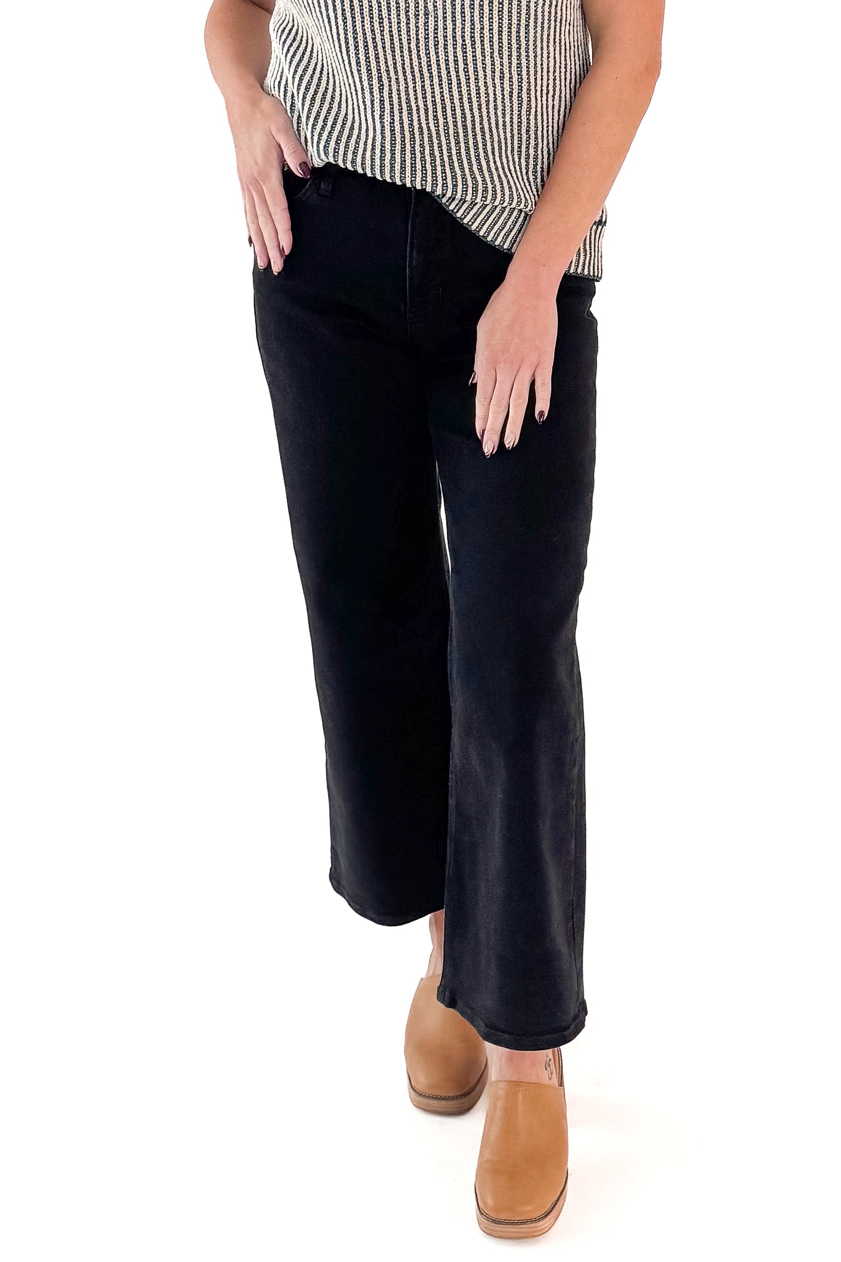 Front view of woman wearing top with black wide leg jeans against white studio background.