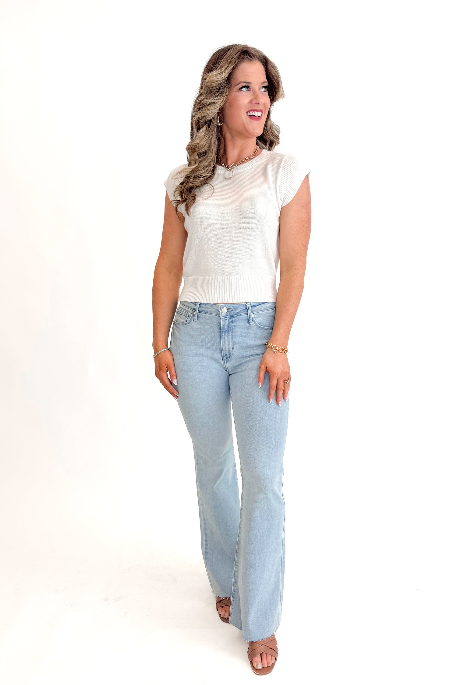 Front view of woman wearing Light Wash Flare Jeans by Just Black Denim with white sweater against white studio background.