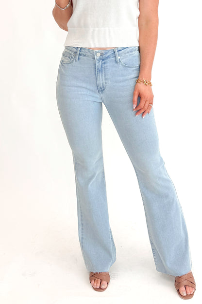 Front detail view of woman wearing Light Wash Flare Jeans by Just Black Denim with white sweater against white studio background.