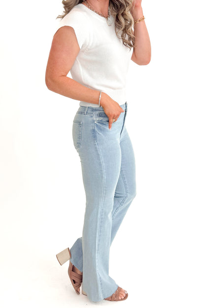 Side view of woman wearing Light Wash Flare Jeans by Just Black Denim with white sweater against white studio background.