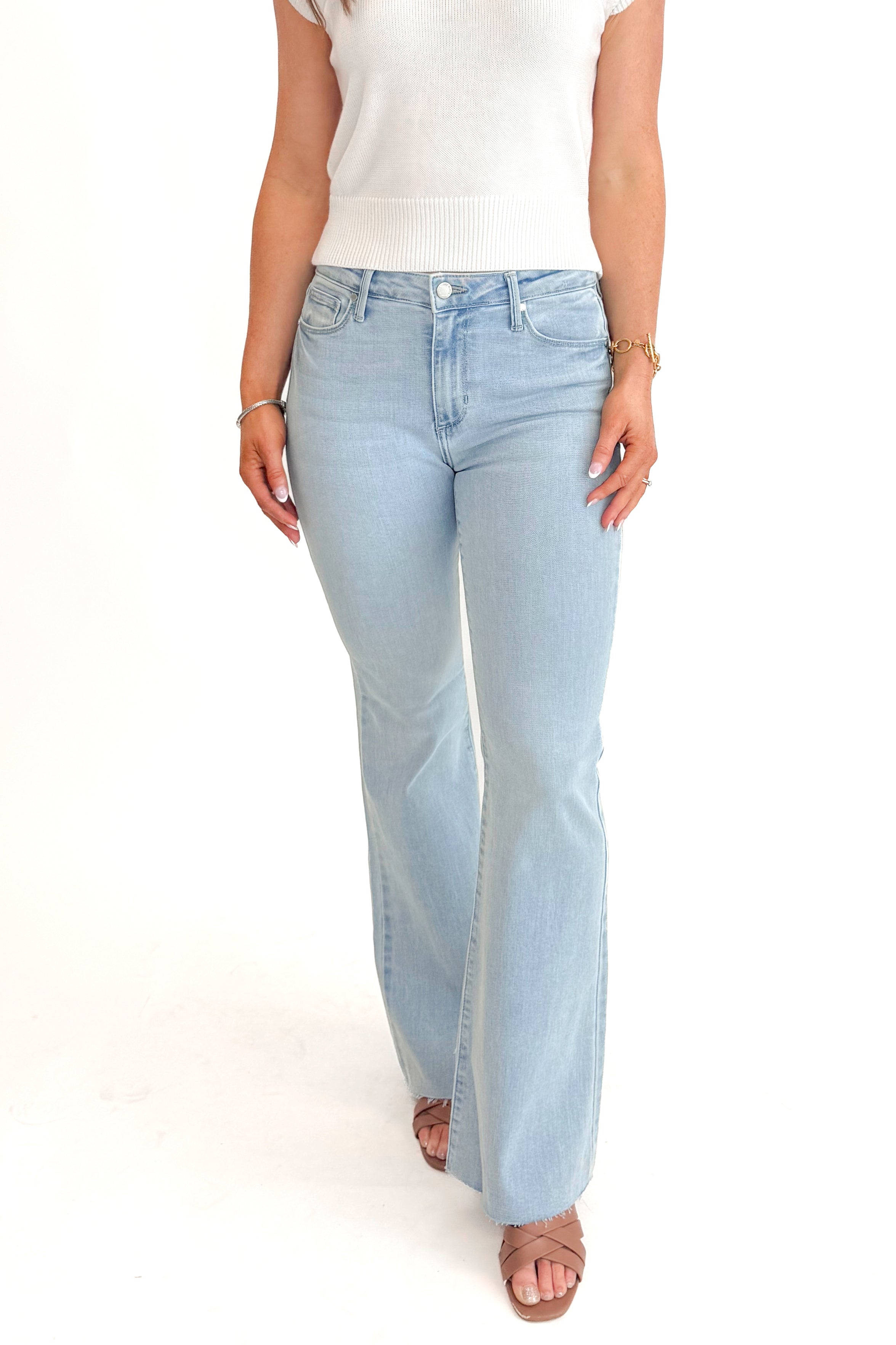 Front detail view of woman wearing Light Wash Flare Jeans by Just Black Denim with white sweater against white studio background.
