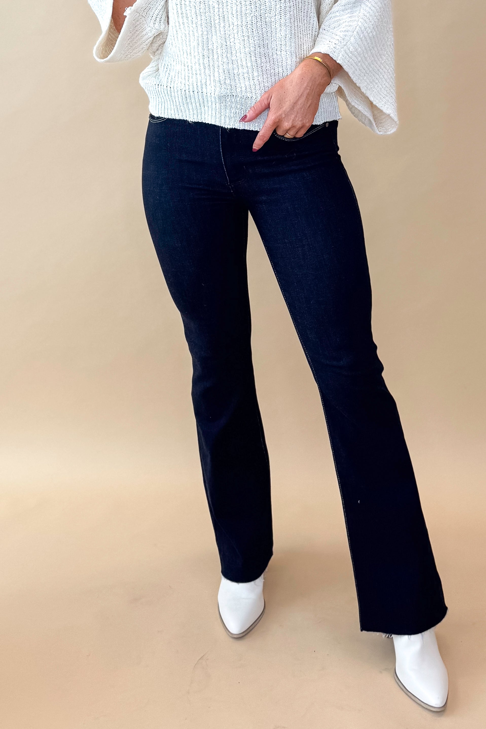 Front view of model wearing top with Super Dark Wash Flare Jeans  against tan studio background.