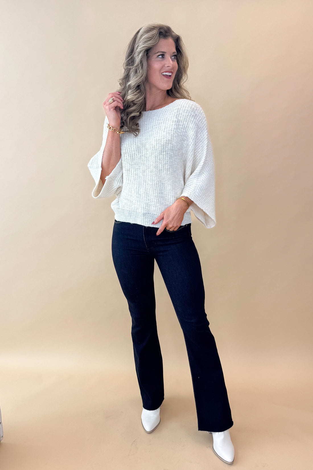 Front view of model wearing top with Super Dark Wash Flare Jeans  against tan studio background.