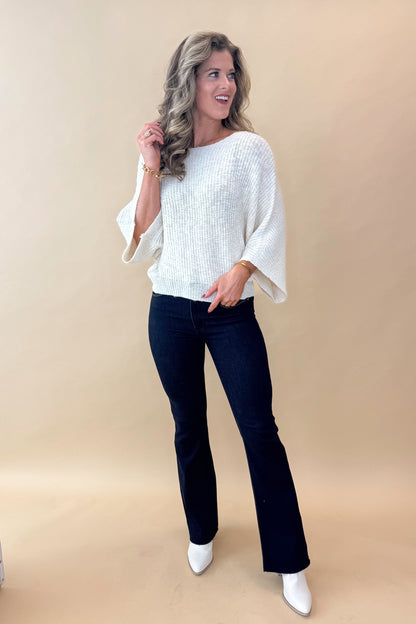 Front view of model wearing top with Super Dark Wash Flare Jeans  against tan studio background.