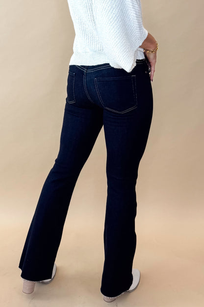 Side view of model wearing top with Super Dark Wash Flare Jeans  against tan studio background.