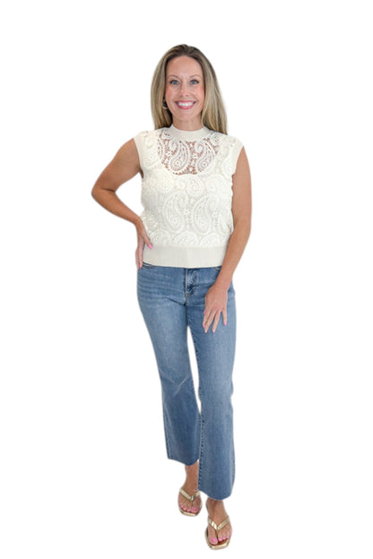 Front view of woman wearing Swagger Boutique’s Beige Crochet Front Sleeveless Sweater with jeans against white studio background.