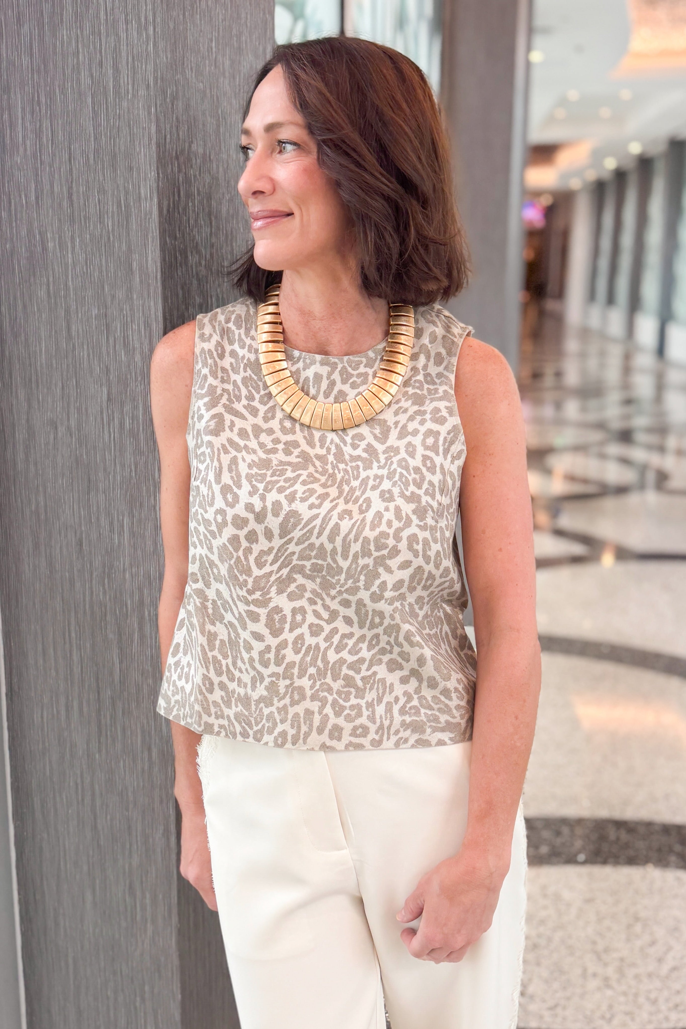 Front detail view of woman wearing Swagger Boutique’s Cream Lace Lined Pants with Metallic leopard print tank standing in a building hallway.