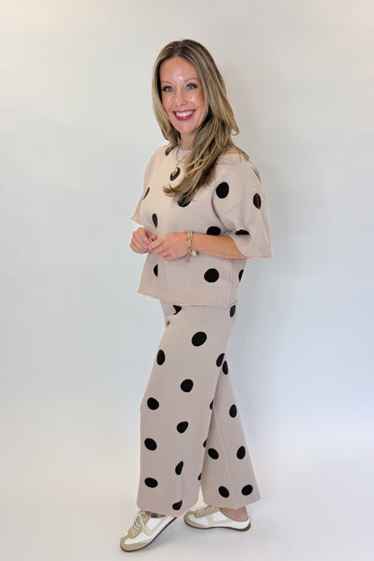 Side view of woman wearing Swagger Boutique’s Beige Polka Dot Short Sleeve Top &amp; Knit Pants against white studio background.
