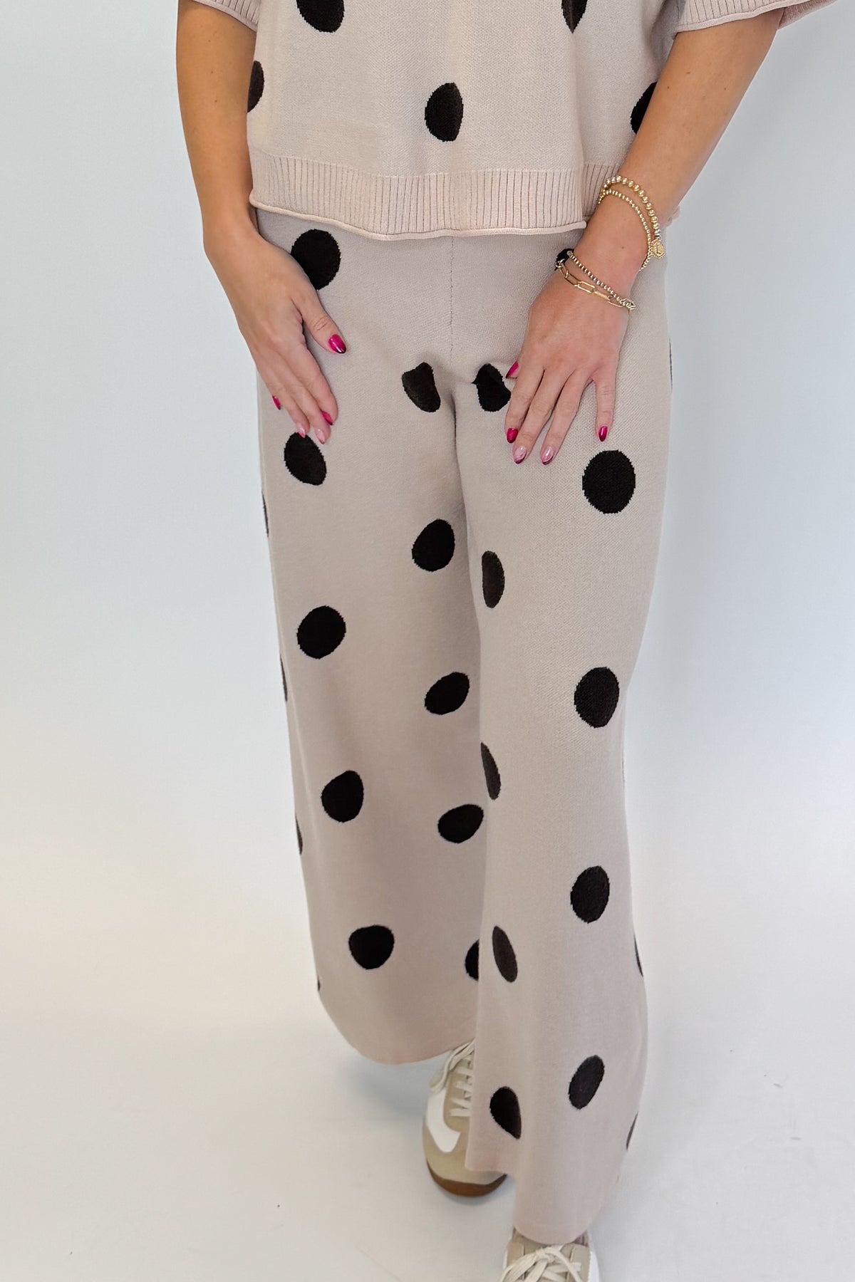 Front detail view of woman wearing Swagger Boutique’s Beige Polka Dot Short Sleeve Top &amp; Knit Pants against white studio background.