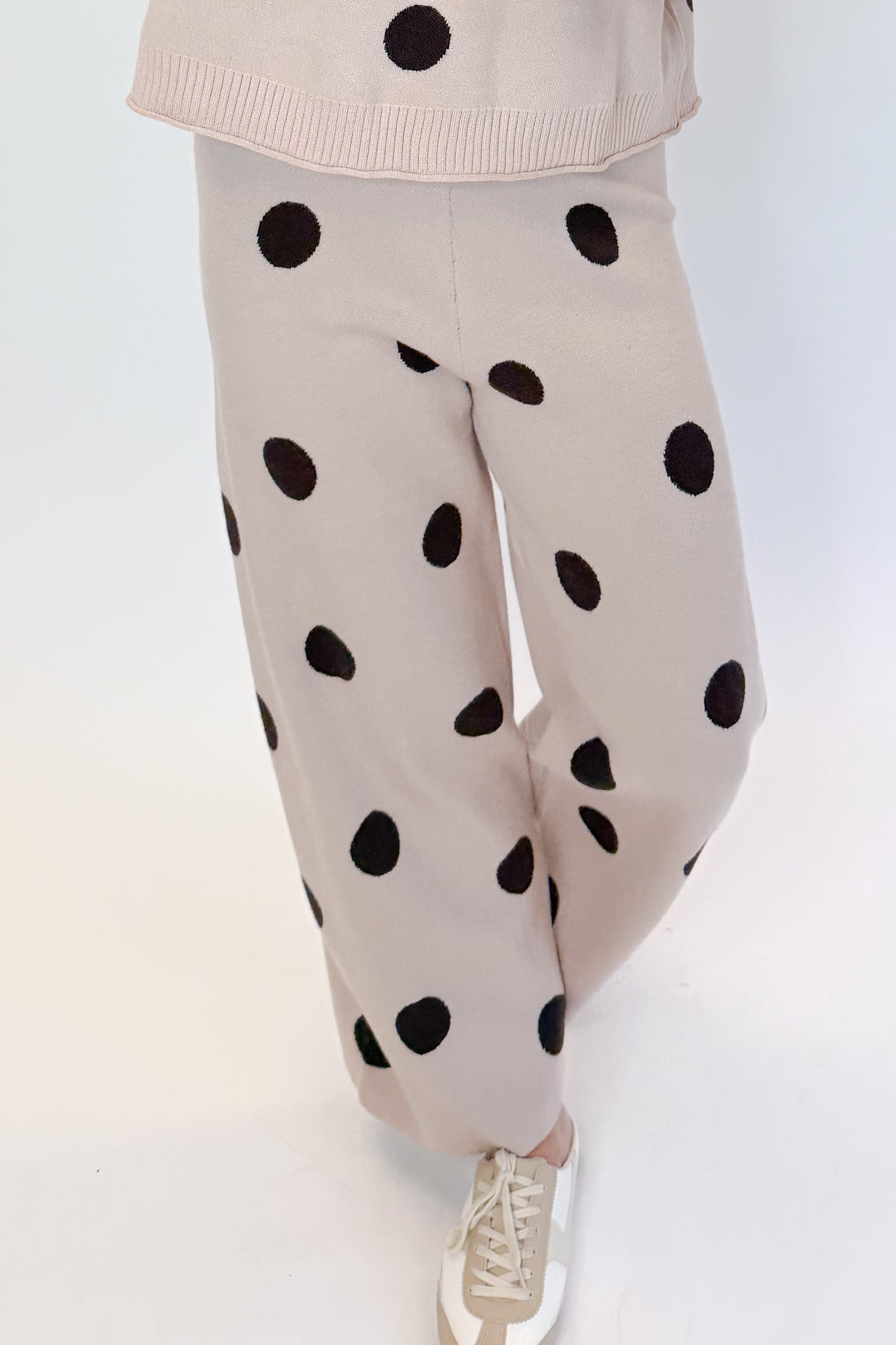 Front detail view of woman wearing Swagger Boutique’s Beige Polka Dot Short Sleeve Top &amp; Knit Pants against white studio background.