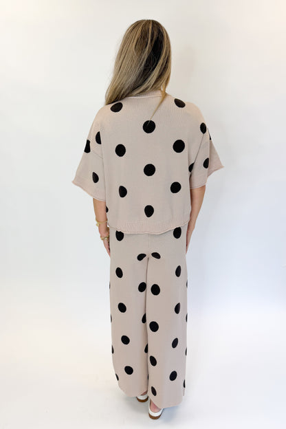 Back view of woman wearing Swagger Boutique’s Beige Polka Dot Short Sleeve Top &amp; Knit Pants against white studio background.