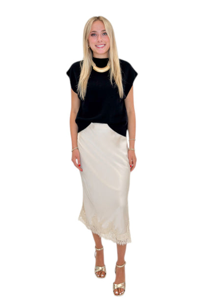 Front view of woman wearing Swagger Boutique’s Beige Satin &amp; Lace Midi Skirt with heels against white studio background.