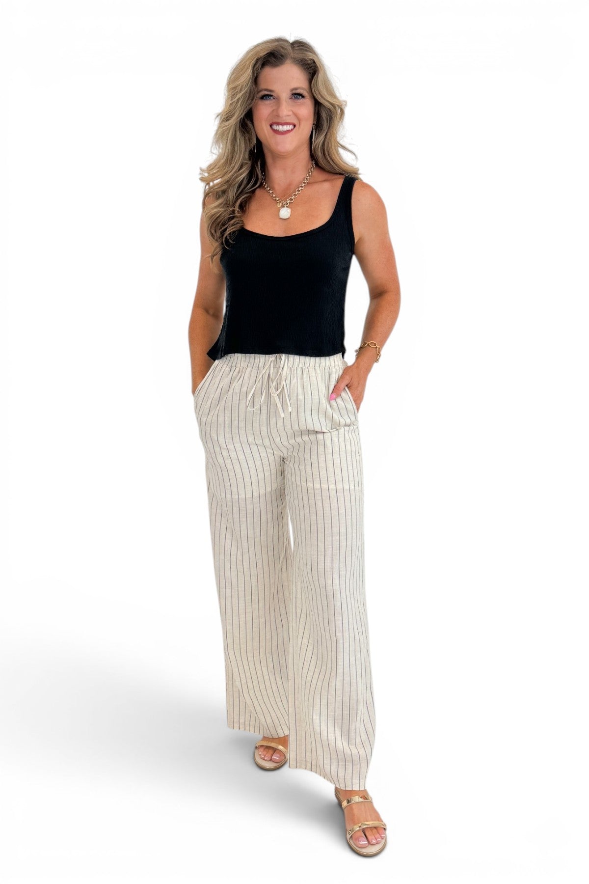 Front view of woman wearing Swagger Boutique’s Beige Striped Wide Leg Linen Pants with top against white studio background.