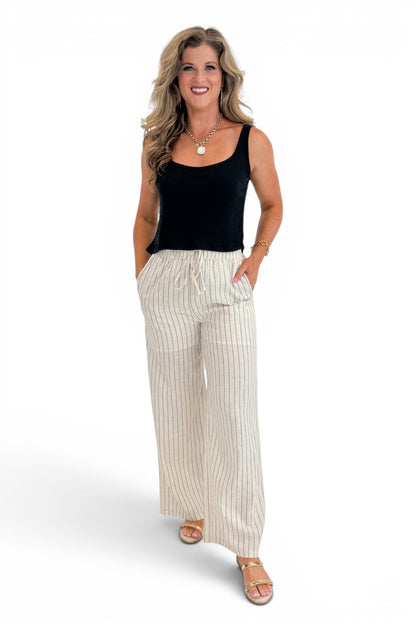 Front view of woman wearing Swagger Boutique’s Beige Striped Wide Leg Linen Pants with top against white studio background.