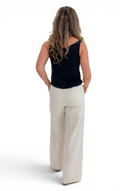 Back view of woman wearing Swagger Boutique’s Beige Striped Wide Leg Linen Pants with top against white studio background.