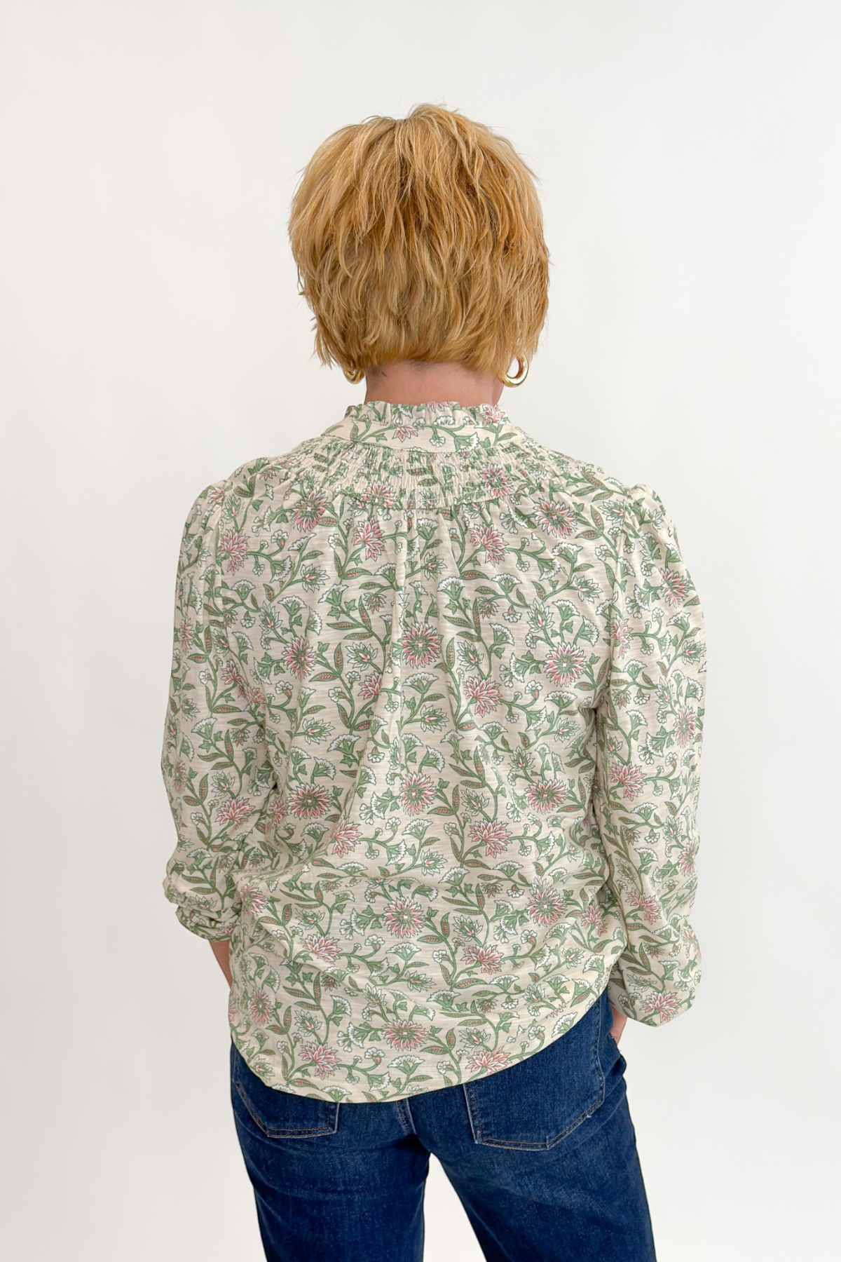 Back view of woman wearing Swagger Boutique’s Beige &amp; Olive Floral Long Sleeve Top with jeans against white studio background.