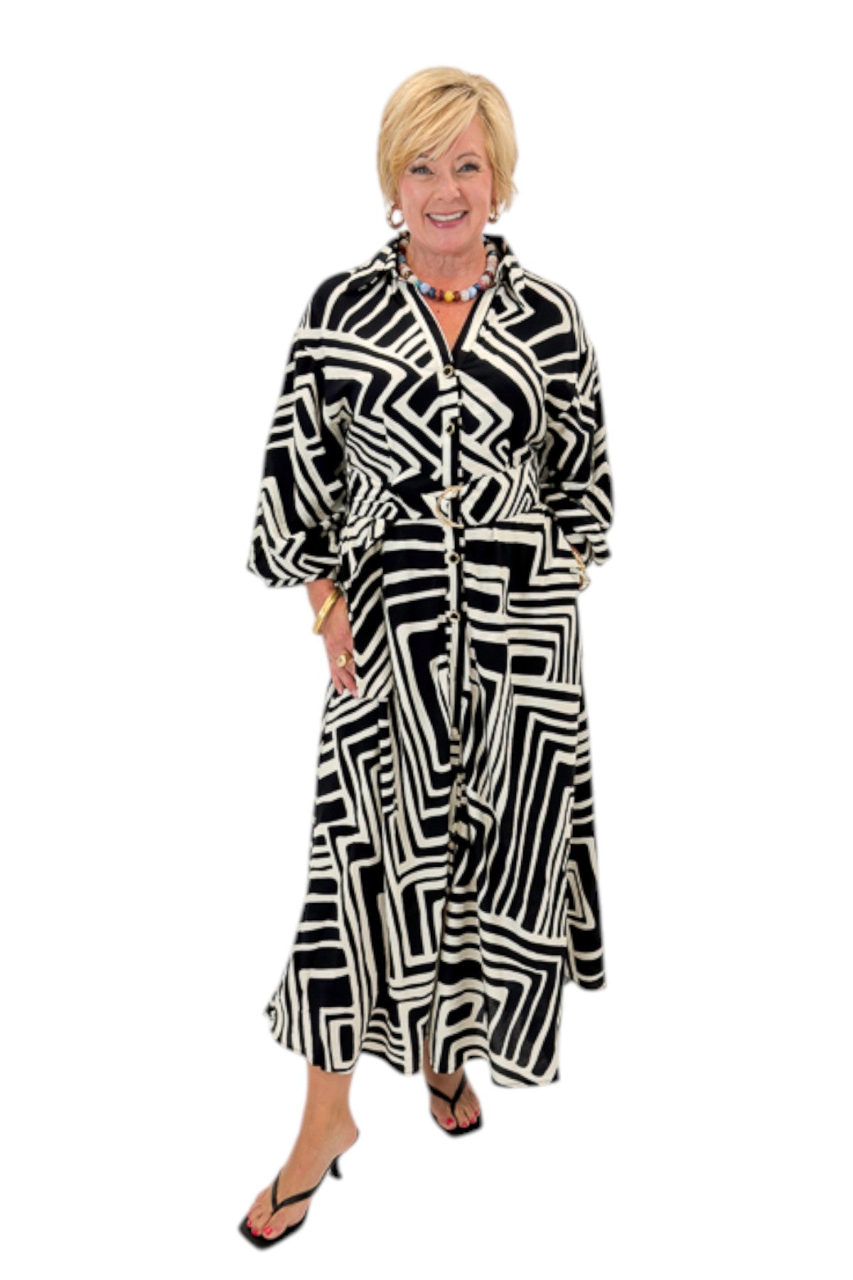 Front view of woman wearing Swagger Boutique’s Black Abstract Print Midi Dress by Entro with heels against white studio background.