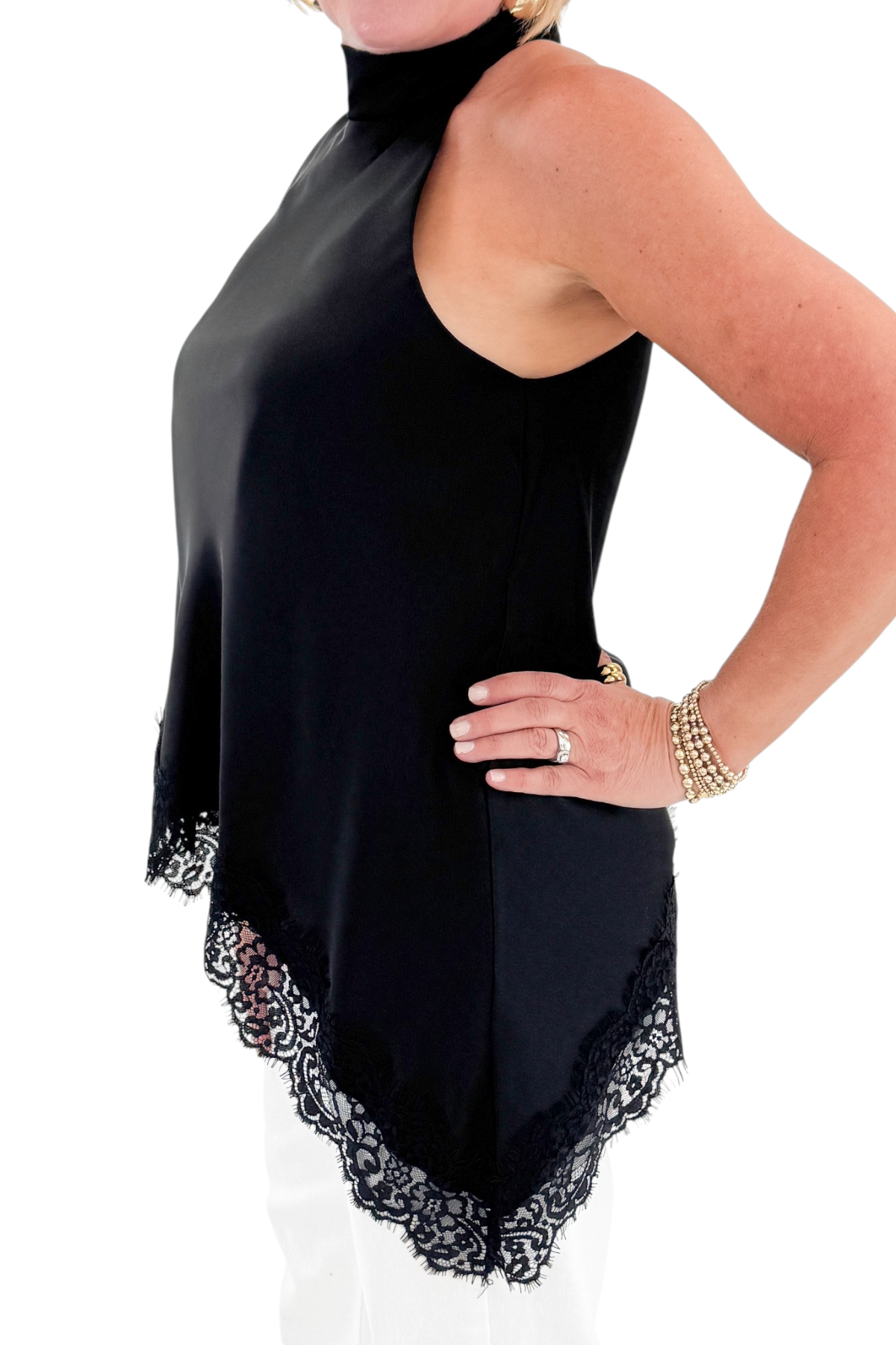 Side detail view of woman wearing Swagger Boutique’s Black Asymmetrical Halter Neck Satin Lace Top with jeans against white studio background.