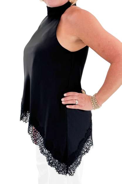 Side detail view of woman wearing Swagger Boutique’s Black Asymmetrical Halter Neck Satin Lace Top with jeans against white studio background.