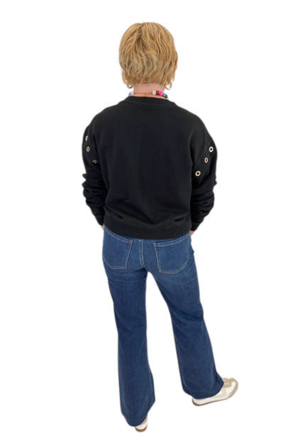 Back view of woman wearing Swagger Boutique’s Black Axel Grommet Sweatshirt by Z Supply with jeans against white studio background.