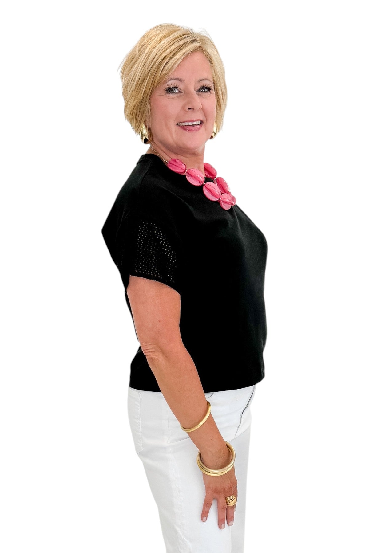 Side view of woman wearing Swagger Boutique’s Black Banyan Top by Z Supply with jeans against white studio background.