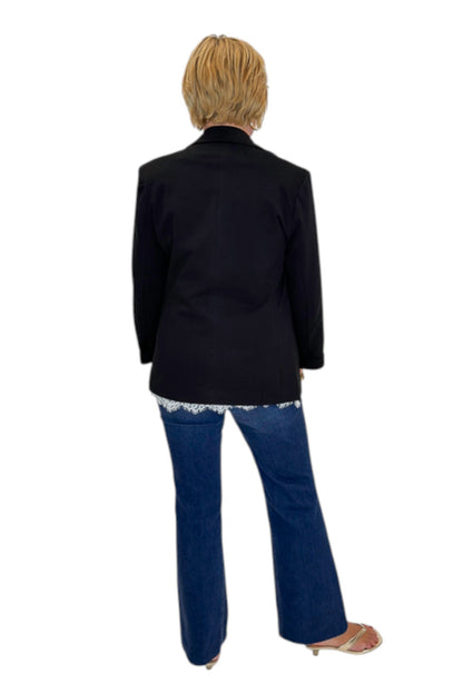 Back view of woman wearing Swagger Boutique’s Black Blazer and Ivory Satin Lace Trim Tank Top by Entro with jeans against white studio background.