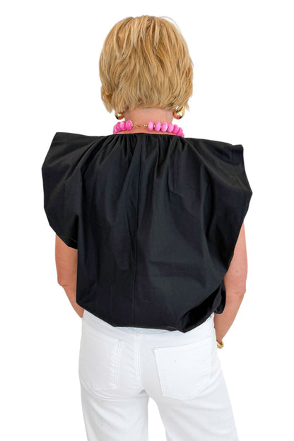 Back view of woman wearing Swagger Boutique’s Black Bubble Hem Pleated Top with jeans against white studio background.