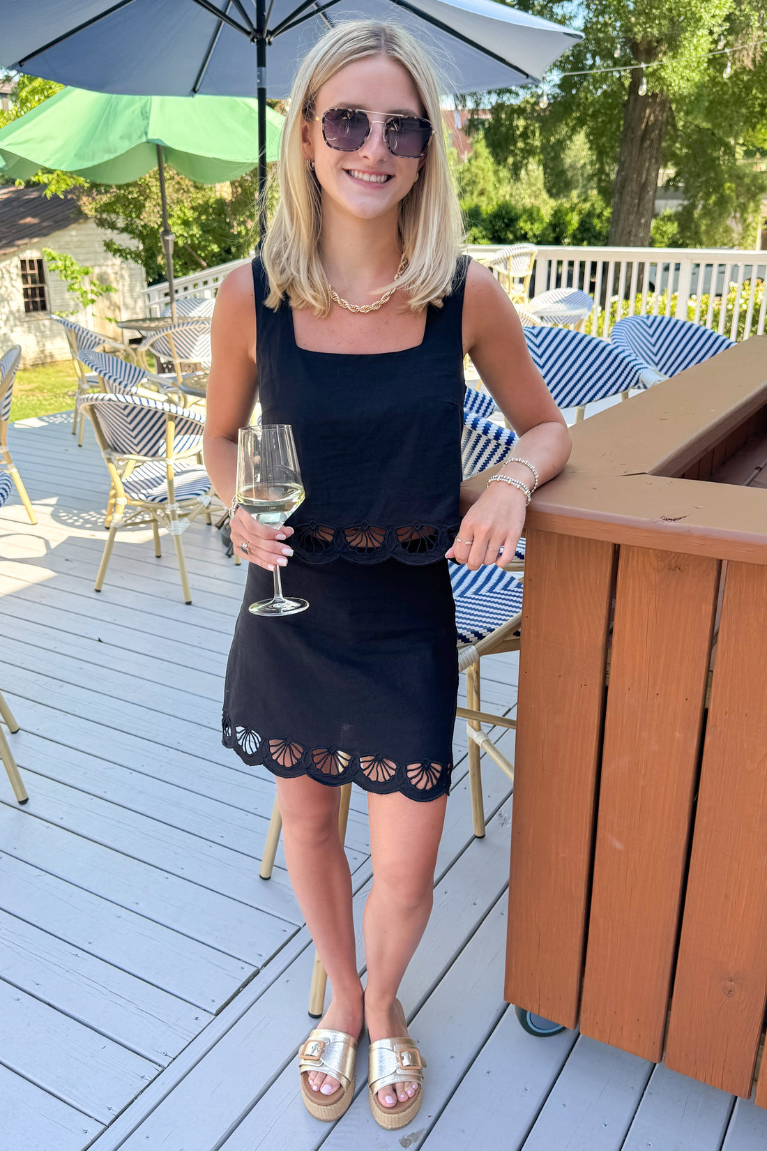 Front view of woman wearing Swagger Boutique’s Black Charlene Embroidery Top &amp; matching mini skirt set by Z Supply standing outside at a restaurant.