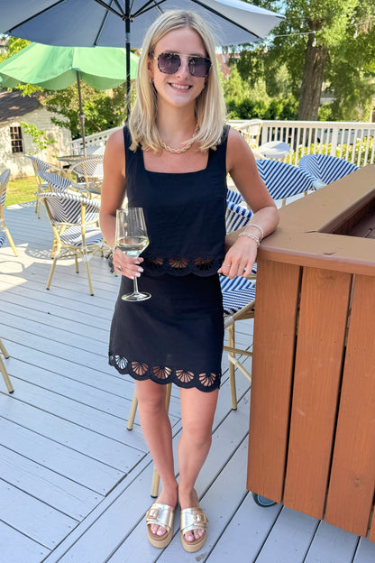 Front view of woman wearing Swagger Boutique’s Black Charlene Embroidery Top &amp; matching mini skirt set by Z Supply standing outside at a restaurant.