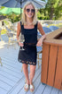 Front view of woman wearing Swagger Boutique’s Black Charlene Embroidery Top & matching mini skirt set by Z Supply standing outside at a restaurant.