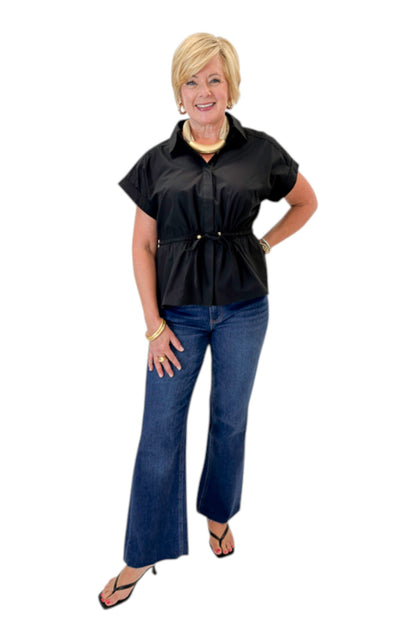 Front view of woman wearing Swagger Boutique’s Black Cinched Waist Short Sleeve Top by Entro with jeans against white studio background.