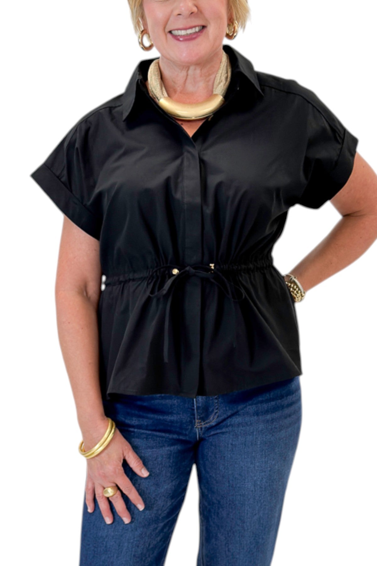 Front detail view of woman wearing Swagger Boutique’s Black Cinched Waist Short Sleeve Top by Entro with jeans against white studio background.