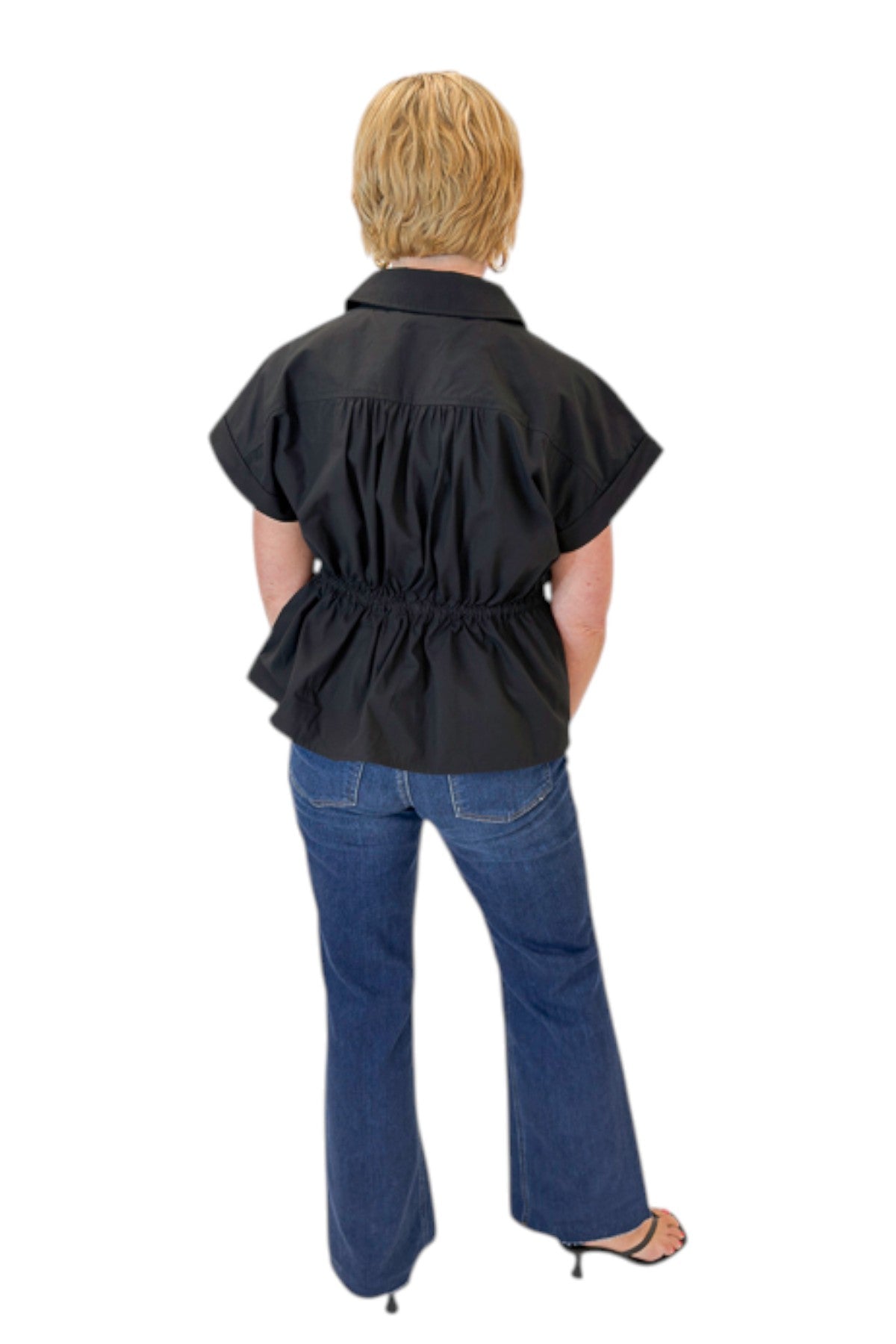 Back view of woman wearing Swagger Boutique’s Black Cinched Waist Short Sleeve Top by Entro with jeans against white studio background.