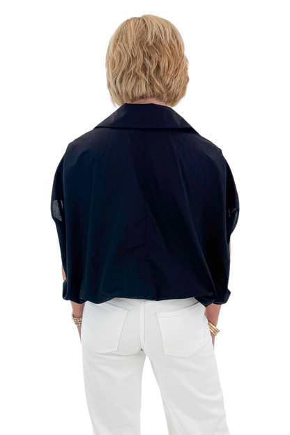 Back view of woman wearing Swagger Boutique’s Black Collared Bubble Hem Top with jeans against white studio background.