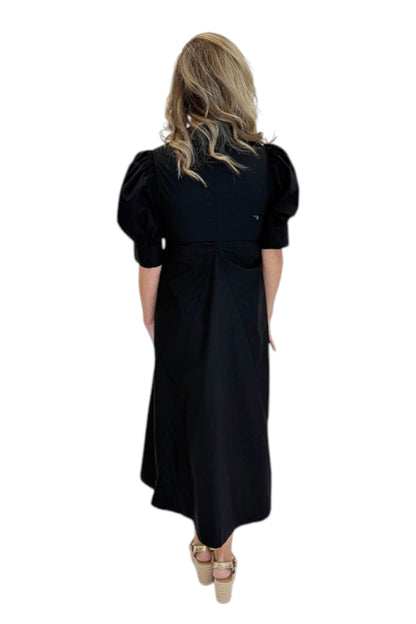 Back view of woman wearing Swagger Boutique’s Black Collared Midi Dress with sandals against white studio background.