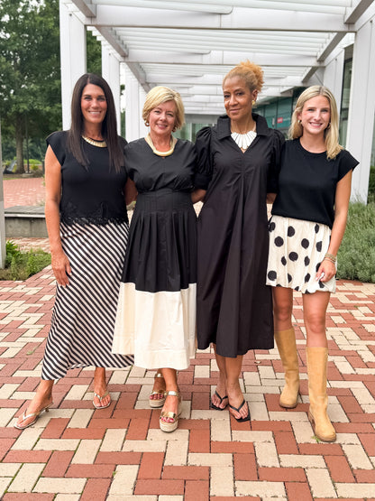 Front view of women wearing Swagger Boutique’s Black &amp; Cream collection items outside by a red brick walkway.