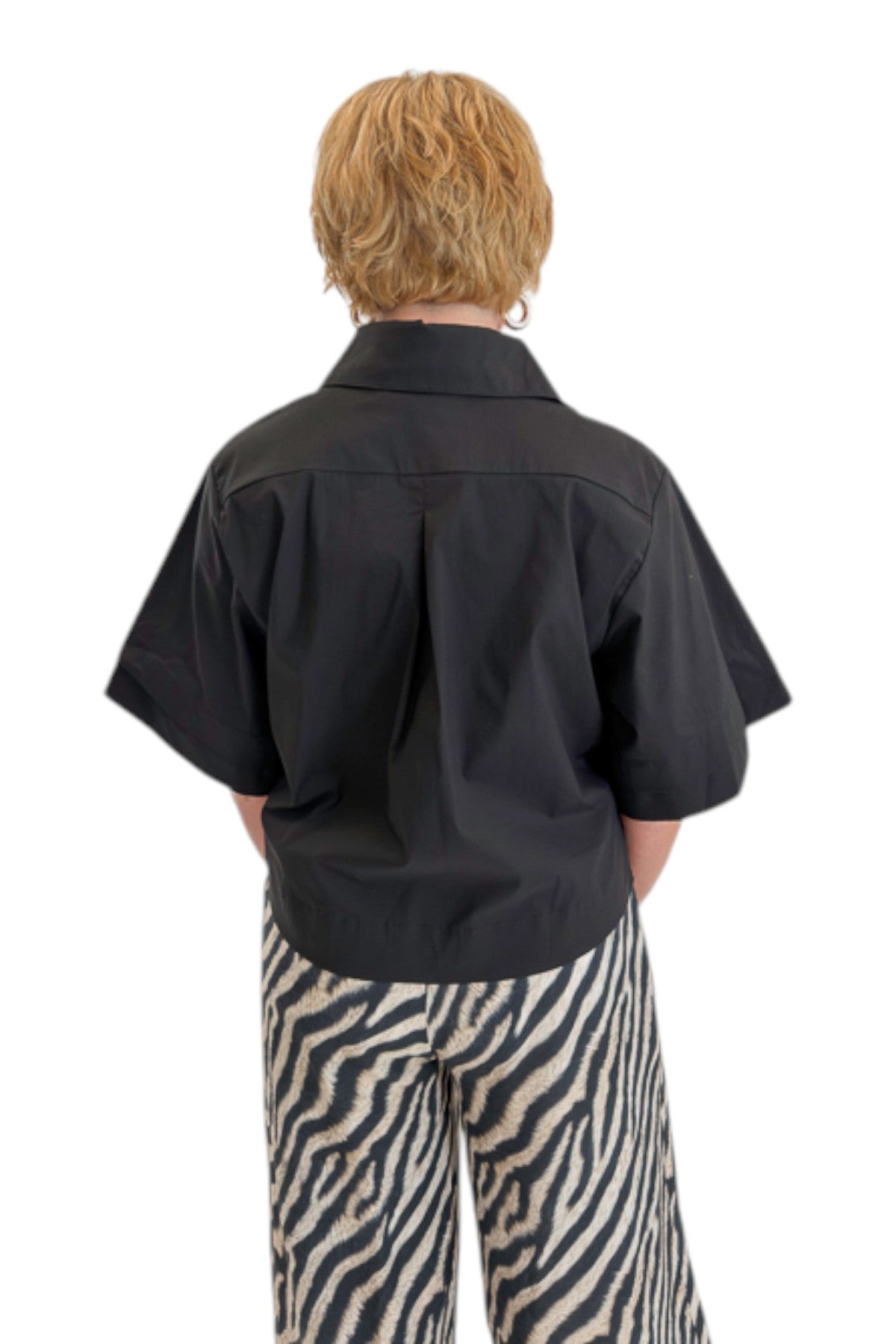 Back view of woman wearing Swagger Boutique’s Black Collared Short Sleeve Top with Zebra Wide Leg Pants by Entro against white studio background.