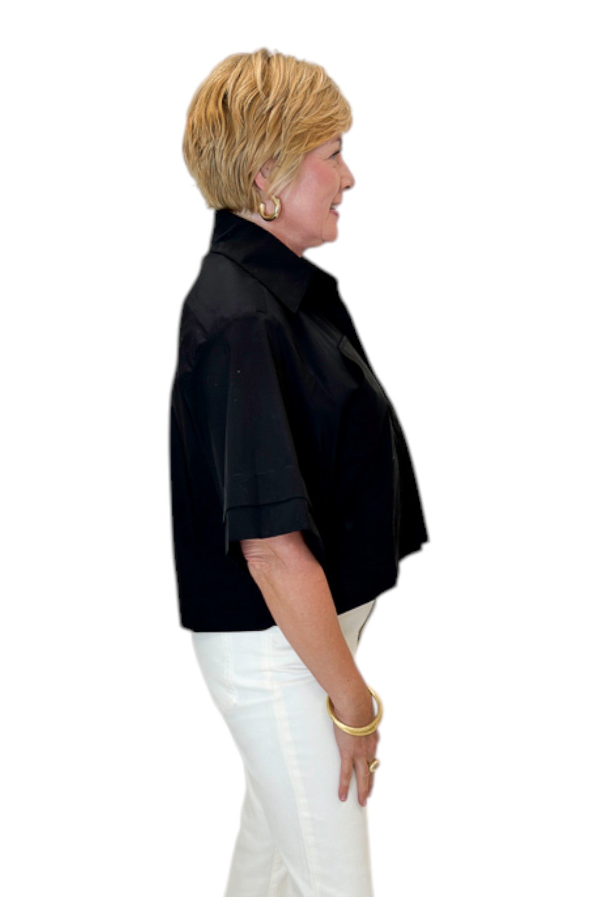 Side view of woman wearing Swagger Boutique’s Black Collared Short Sleeve Top with jeans against white studio background.