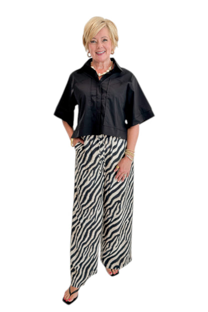 Front view of woman wearing Swagger Boutique’s Black Collared Short Sleeve Top with Zebra Wide Leg Pants by Entro against white studio background.