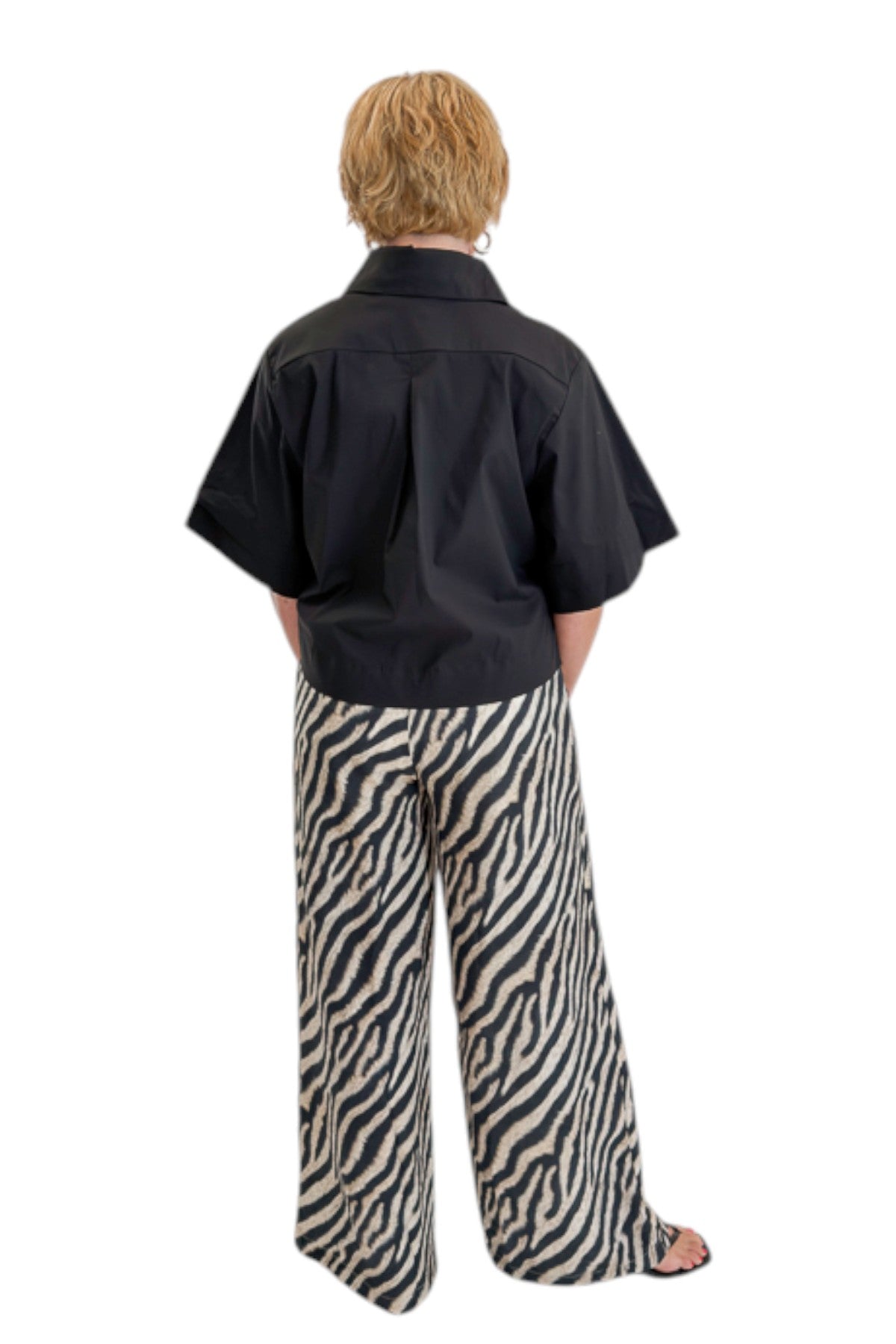 Back view of woman wearing Swagger Boutique’s Black Collared Short Sleeve Top with Zebra Wide Leg Pants by Entro against white studio background.