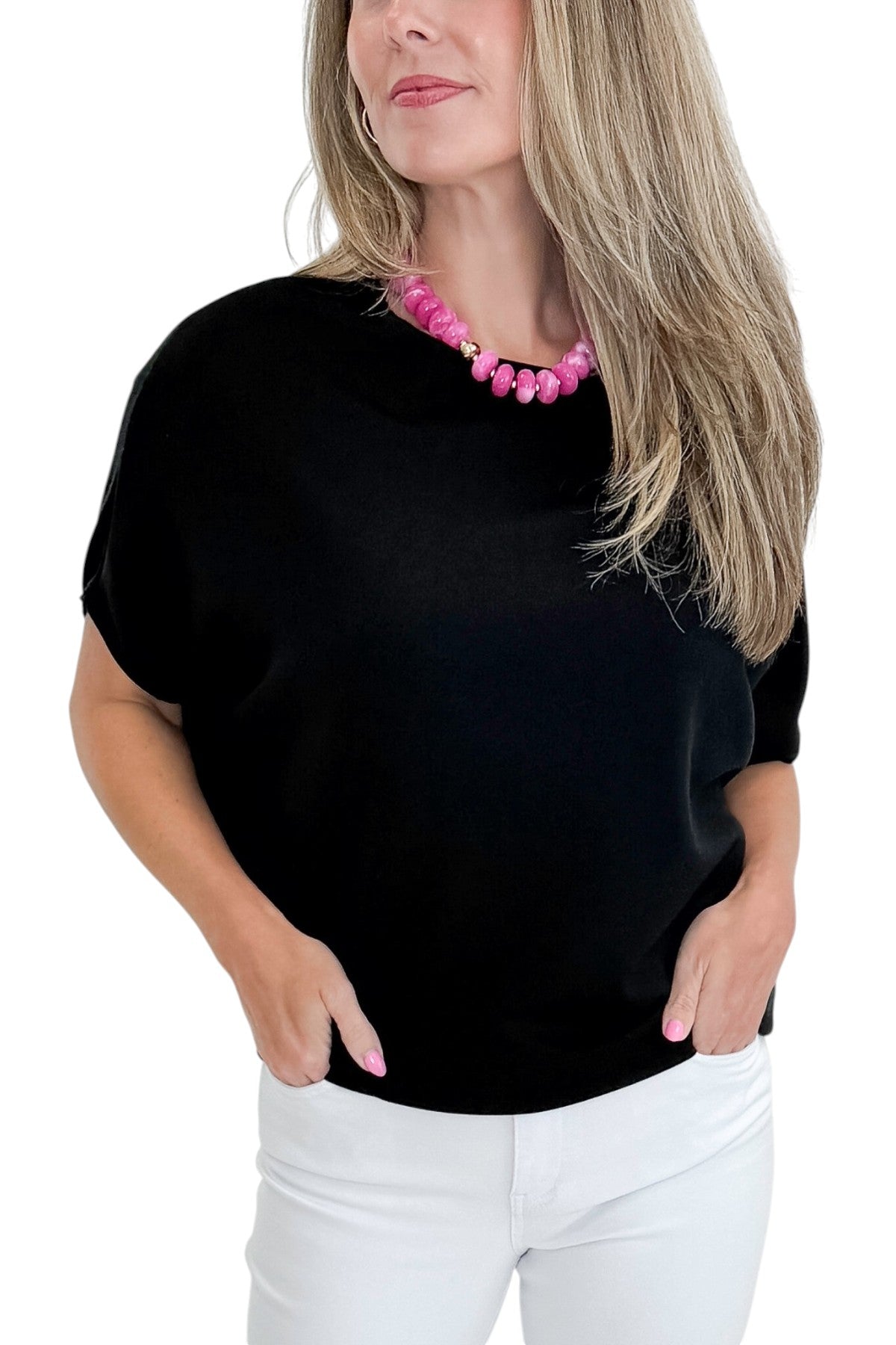 Front detail view of woman wearing Swagger Boutique’s Black Dolman Sleeve Top with jeans against white studio background.