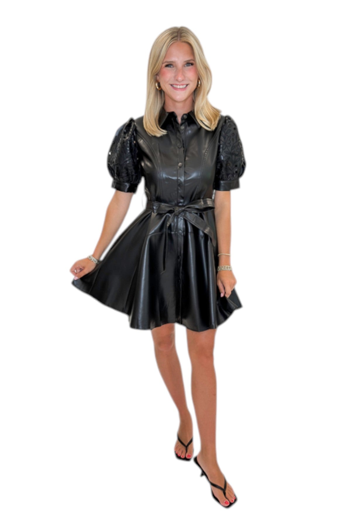 Front view of woman wearing Swagger Boutique’s Black Embroidered Faux Leather Dress with heels against white studio background.