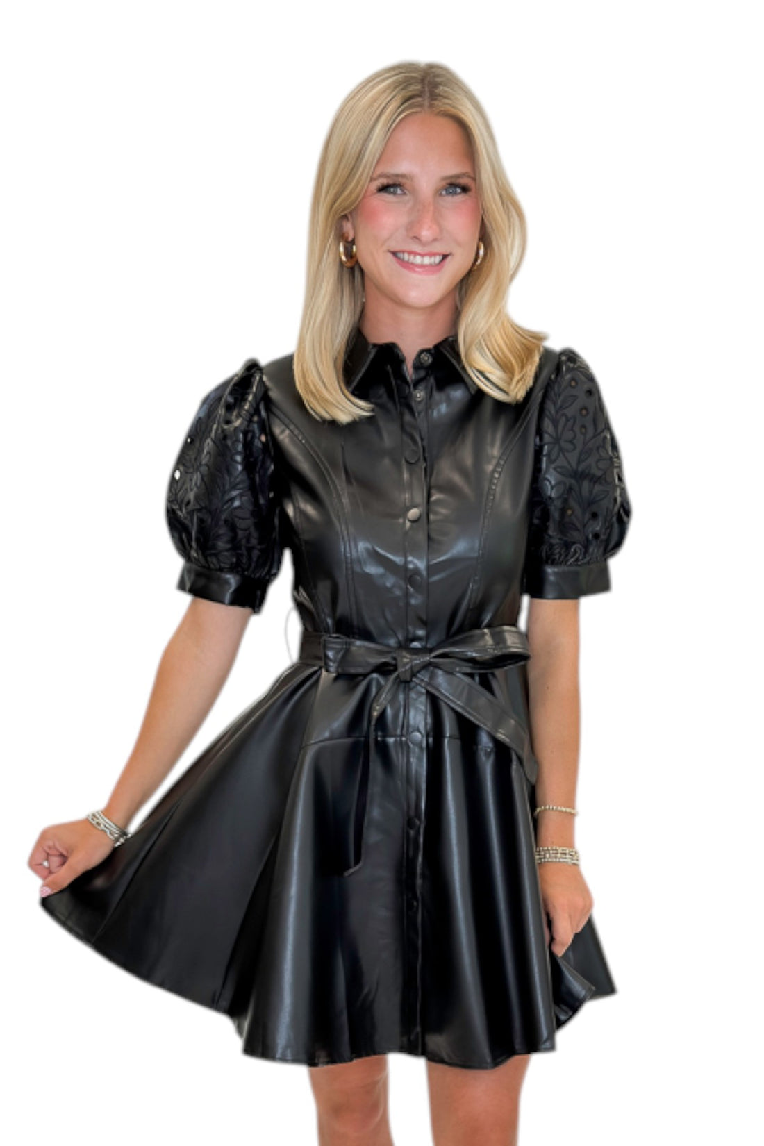 Front view of woman wearing Swagger Boutique’s Black Embroidered Faux Leather Dress with heels against white studio background.