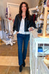 Front view of woman wearing Swagger Boutique’s Black Faux Leather Jacket With Layered Shirt with jeans standing at the store.