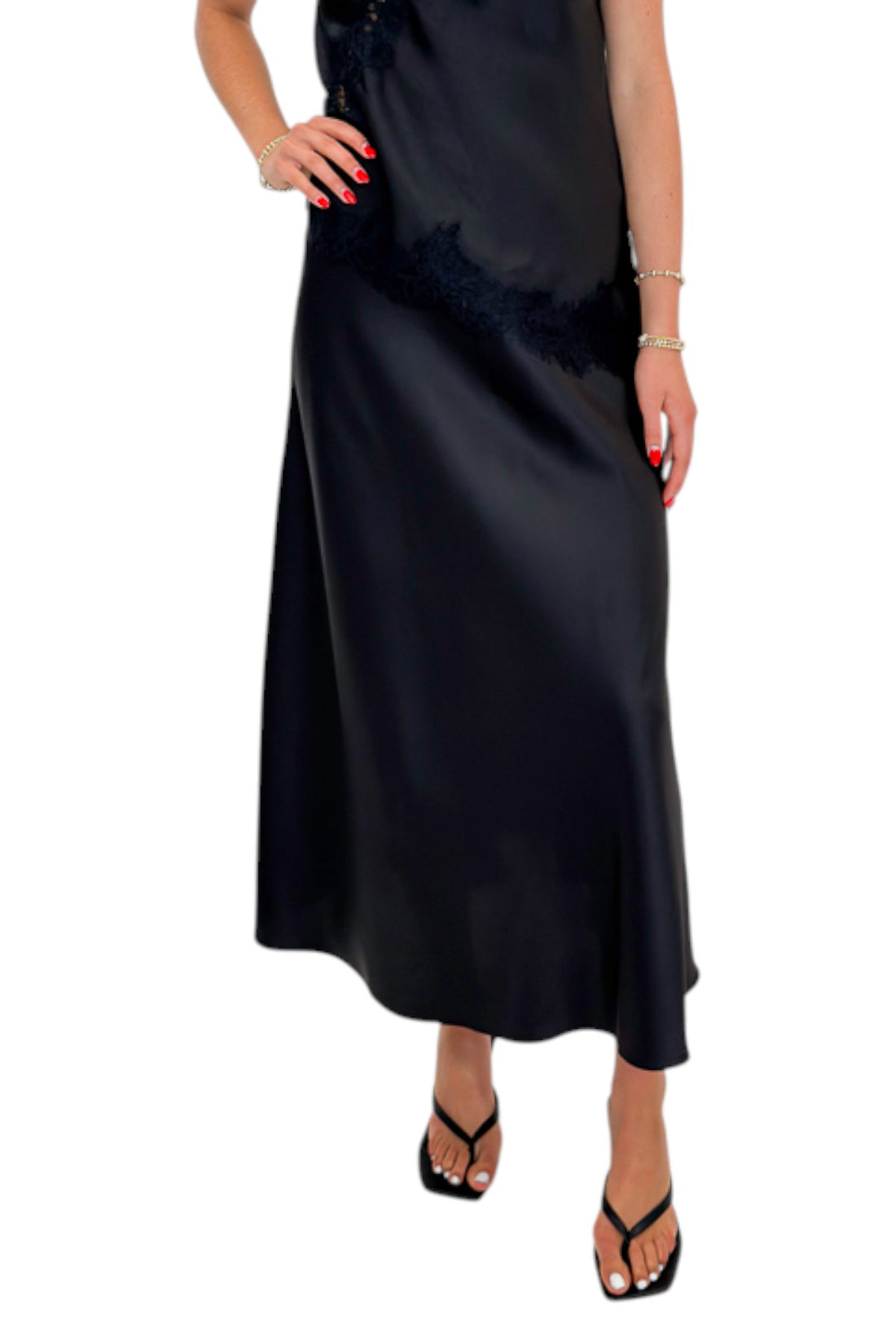 Front view of woman wearing Swagger Boutique’s Black Lace Satin Tank with Black Flare Satin Midi Skirt against white studio background.