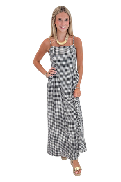 Front view of woman wearing Swagger Boutique’s Black Gingham Maxi Dress with sandals against white studio background.