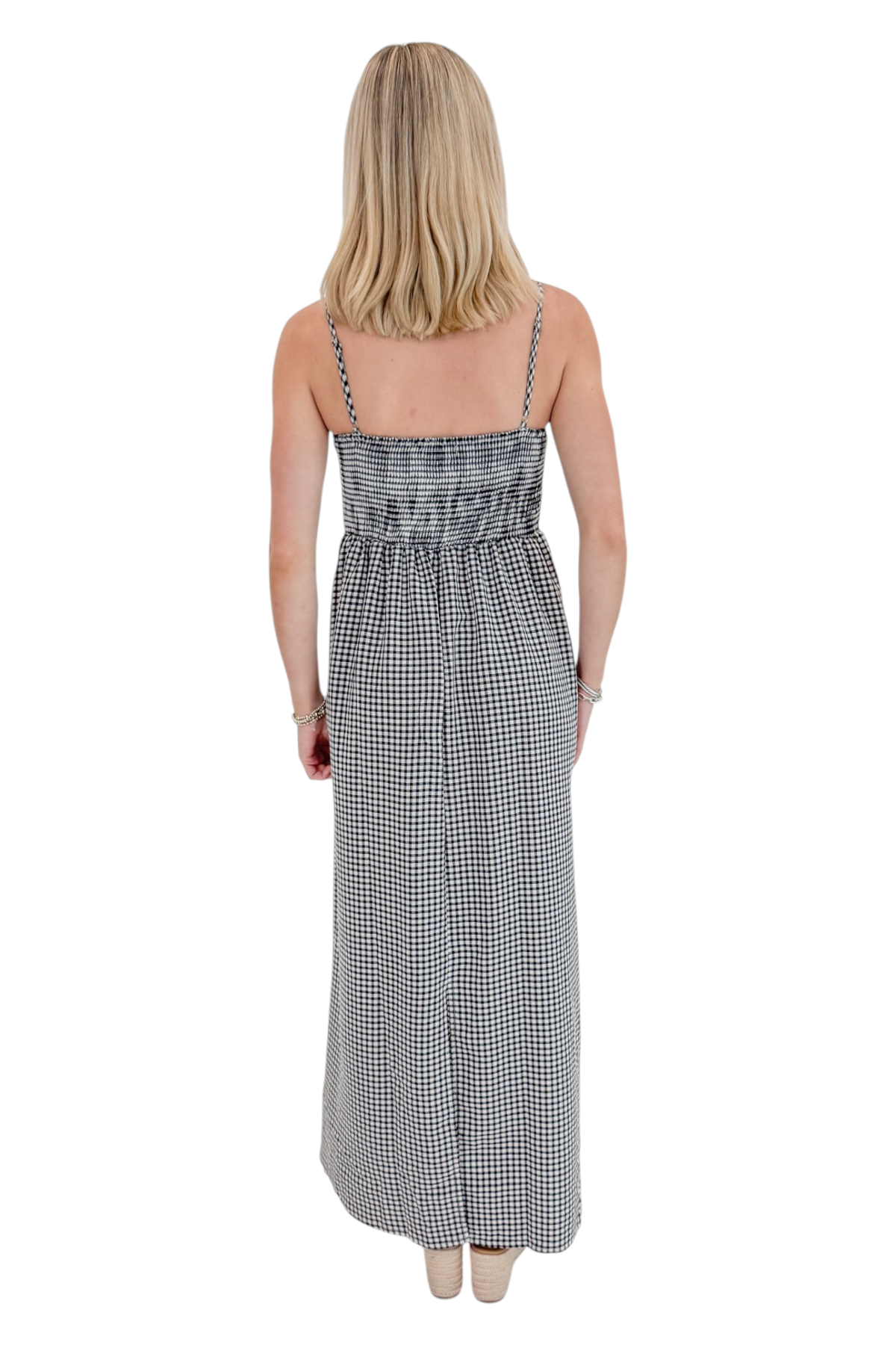 Back view of woman wearing Swagger Boutique’s Black Gingham Maxi Dress with sandals against white studio background.