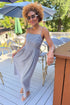 Front view of woman wearing Swagger Boutique’s Black Gingham Maxi Dress with sandals standing outside at a restaurant.